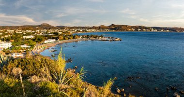 Rodos 'taki Faliraki tatil köyünün panoraması. Deniz, sahil ve çevresindeki tepeler.