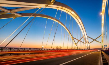 Güzel, modern bir otoyol köprüsünden geçen gece yol boyunca araba izleri var.