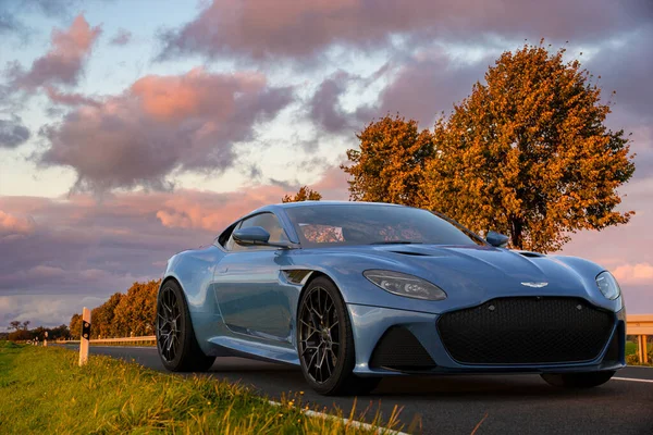 日落时分 Aston Martin Dbs超级腿在一条风景秀丽的路上 — 图库照片