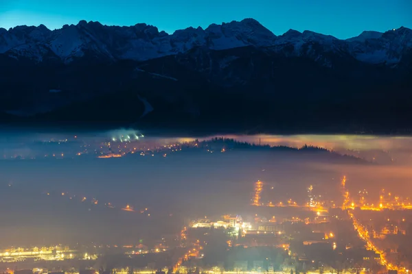 A town in a mountain valley covered with a sheet of morning fog before sunrise-Zakopane, Poland