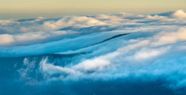 日の出に照らされた山の頂上には雲が立ち込めている — ストック写真