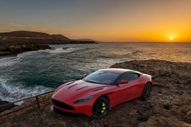 Aston MArtin DB 11 gün batımında uçurumun kenarında.