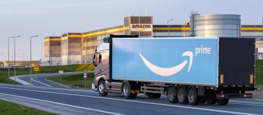 Amazon logosu olan yarı karavanlı bir kamyon Amazon lojistik merkezine gidiyor.