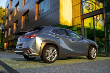 Modern bir ofis binasının otoparkında lüks bir Lexus UX geçidi.
