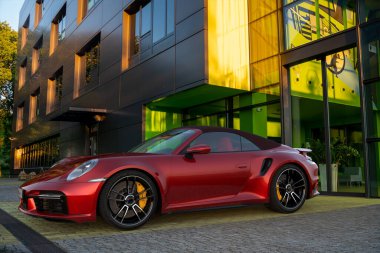 Porsche 911 Turbo S Cabriolet modern bir ofis binasının önüne park etmiş.