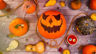 Ahşap bir masada balkabağı sonbahar Cadılar Bayramı manzarası. Korkunç Jack Fenerleri ve balkabakları arasında yürüyen örümcekler. Korkunç cadılar bayramı sahnesi