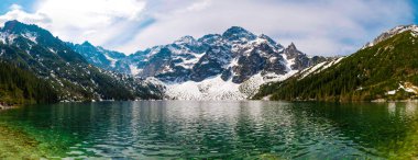 Yüksek kayalık dağlar ve kristal berraklığında turkuaz göl yüksek çözünürlüklü panorama. Tatra Ulusal Parkı, dağlarda karla kaplı bir göl..
