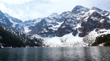 Yüksek kayalık dağlar ve kristal berrak turkuaz göl manzarası. Tatra Dağları, dağlarda kar panoramik manzaralı bir göl..