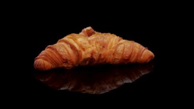 Taze pişmiş kruvasan. Siyah arka planda dönen Fransız kruvasanı. Taze ve lezzetli Fransız kahvaltısı..