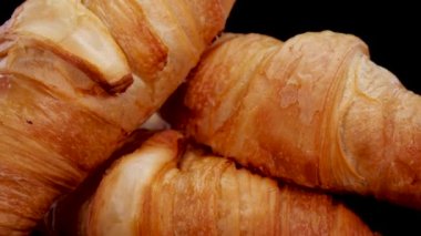 Taze pişmiş kruvasanlar, yakından bakın. Siyah arka planda dönen Fransız kruvasanları. Taze ve lezzetli Fransız kahvaltısı..