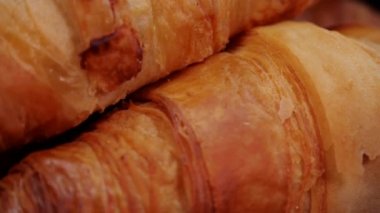 Taze pişmiş kruvasanlar makro manzarayı kapatır. Siyah arka planda dönen Fransız kruvasanları. Taze ve lezzetli Fransız kahvaltısı..