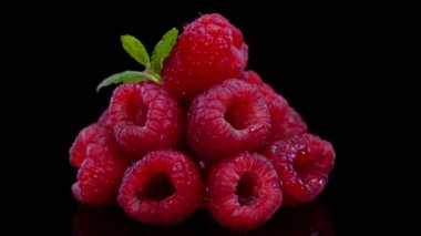 Siyah arka planda dönen ahududu, yakın plan, manzara. Taze, sert ve lezzetli ahududu ve 4 bin dolarlık nane yaprağı. Çiğ vejetaryen yaz atıştırmaları, orman meyveleri..