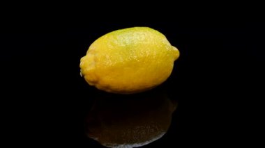 Siyah arka planda dönen sarı limon. Taze, mükemmel, organik canlı sarı limon 4K.