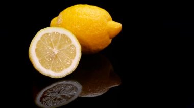 Siyah arka planda dönen sarı limon. Taze, mükemmel, organik canlı sarı limon 4K.