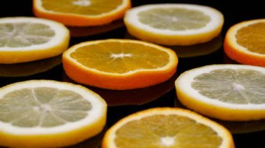 Siyah arka planda dönen turunçgil dilimleri. 4K içinde organik portakal ve limon dilimleri..