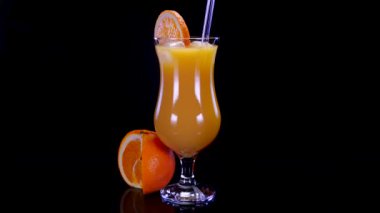 Siyah arka planda dönen taze sıkılmış portakal suyu. Taze, mükemmel organik portakal suyu 4K. 