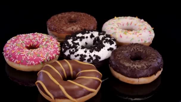 Различные Пончики Глазурью Красочные Посыпки Вращаются Черном Фоне Сладкий Пончик — стоковое видео