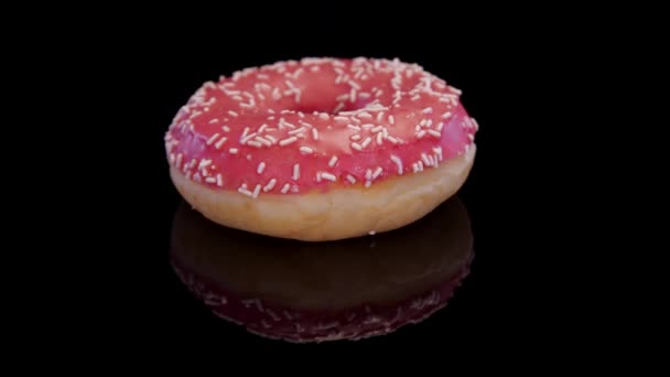 ピンクのアイシングと砂糖でドーナツ黒の背景に回転を振りかける 霜降りで甘いドーナツと隔離された振りかける コンセプト 甘い食べ物 パン屋 ジャンクフード — ストック動画