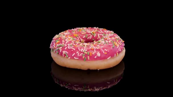 Donut Mit Rosa Zuckerguss Und Buntem Streusel Auf Schwarzem Hintergrund — Stockvideo