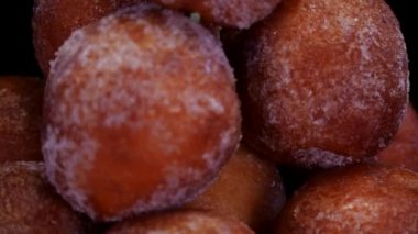 Siyah arka planda dönen süzme peynirli çörekler, yakın görüş. Taze fırınlanmış kuark peyniri mini çörek topları şekere bulanmış.. 