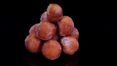 Siyah arka planda dönen süzme peynirli çörekler. Taze fırınlanmış kuark peyniri mini çörek topları şekere bulanmış.