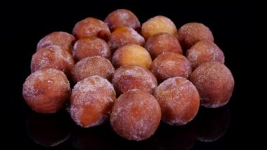 Siyah arka planda dönen süzme peynirli çörekler. Taze fırınlanmış kuark peyniri mini çörek topları şekere bulanmış.