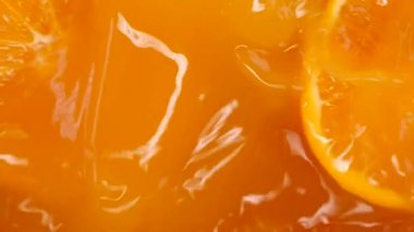 Portakal suyu dökülür ve portakal suyuna karışır ve ikiye bölünür. Taze portakallı bir masa. Meyveler suya sıçrıyor.