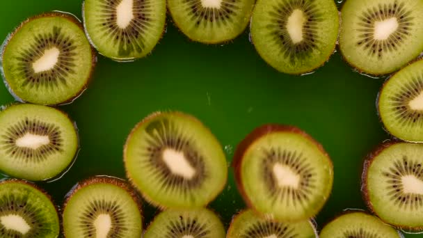 キウイスライスはゆっくりと動きながら水やキウイジュースに飛び込みます おいしい緑の夏の果物 — ストック動画