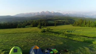 Gün doğarken dağlarda kamp kurun. Çayırın ortasında yüksek dağ manzaralı iki çadır. Arka planda Tatra dağları var. Kavram: göçebeler, açık havada seyahat, vahşi doğada yürüyüş, yürüyüş.