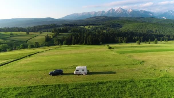 トレーラー山の中でキャラバン トレーラーキャラバンとRv車の空中ビューは 単独で山の景色を牧草地の真ん中に駐車しました 野生のキャンプでの家族の休暇 — ストック動画