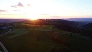 Dağ yolunda gün doğumu, hava manzarası. Dağ köyünde destansı ve renkli bir gün doğumu. Dağ manzarasında gün doğumunun sinematik hava görüntüsü.