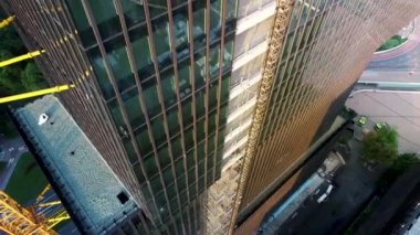 İnşaat halindeki gökdelenin havadan görüntüsü. Çok katlı, modern, yüksek katlı camdan bir bina inşa ediliyor. Güzel ufuk çizgisi manzarası.