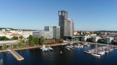 Modern bir sahil şehrinde beyaz yatlar ve yelkenlilerle dolu liman manzarası. Yazın güneşli bir günde tekneli Marina. Arka planında gökdelenler olan modern bir kasabada iskele..