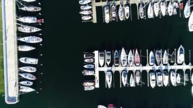 Modern bir sahil şehrinde beyaz yatlar ve yelkenlilerle dolu bir liman manzarası. Yazın güneşli bir günde tekneli Marina. Arka planında gökdelenler olan modern bir kasabada iskele..