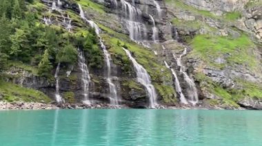 Göl kenarındaki dağlarda şelale. Oeschinnensee. Kandertal. Bernese Oberland. Canton Bern. İsviçre. 