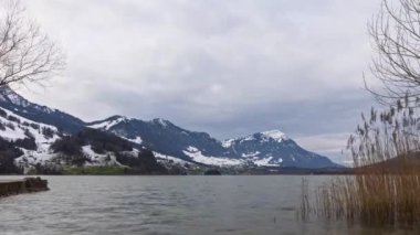 Dağlarda kar ve hareket eden bulutlarla kaplı bir gölün hızlandırılmış panoramik görüntüsü. Rigi Dağı 'nın manzarası. Lauer Gölü. Canton Schwyz, İsviçre. 