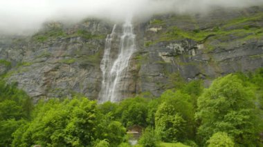 Dağlarda şelale. Dağların tepesindeki kayalardan düşen su bulutlarla kaplıdır. Mrrenbachfall, Lauterbrunnen Vadisi, Bernese Oberland, Canton Bern, İsviçre.