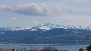 Dağın ön planında gölün olduğu zaman dilimi manzarası. Dağın etrafında dans eden bulut. İsviçre.
