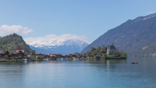時間経過背景に雪の山と半島と旧城のビュー Iseltwald Lake Brienz Canton Bern スイス — ストック動画