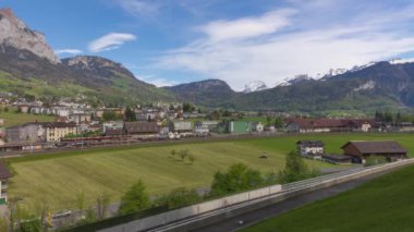Zaman ayarlı, traktör tren istasyonunun yakınında balya topluyor. İsviçre Alpleri 'nde bir kasaba. Seewen, Canton Schwyz, İsviçre.
