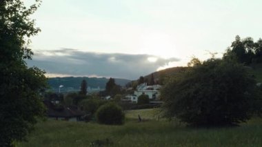 Zaman aşımı günbatımı. Tepelerin üzerinde güneş ışınları olan bulutlar. İsviçre.