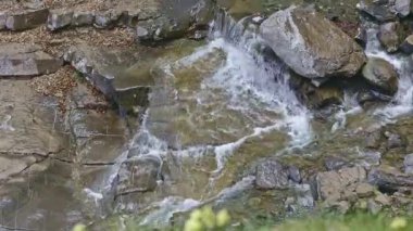 Dağlardaki kayalar arasında küçük bir şelalenin görüntüsü. Islak kaya ve taşların arasından akan sular.