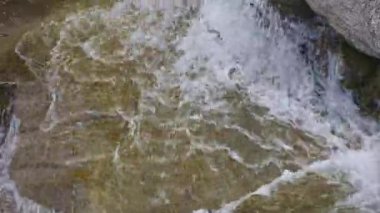 Dağlardaki kayalar arasında küçük bir şelalenin görüntüsü. Islak kaya ve taşların arasından akan sular.