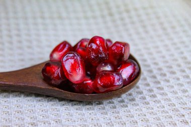 Tahta bir kaşıkta nar tohumlarını yakın çekim. Ahşap kaşık, keten peçetenin üzerinde kırmızı olgun nar tohumları. Tahta kaşıkta nar tohumları..