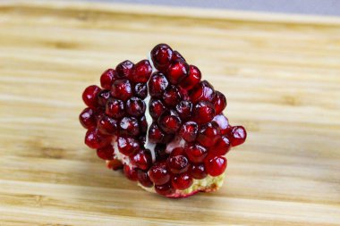 Tahta tepside kırmızı çekirdekli bir nar parçası. Nar tohumları. Bir parça olgun nar meyvesi..