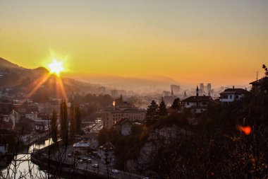 Saraybosna ve Saraybosna Belediye Binası 'nın üzerinde güzel bir gün batımı. Şehrin güzel manzarası ve Saraybosna şehrinin diğer manzaralarının siluetleri..