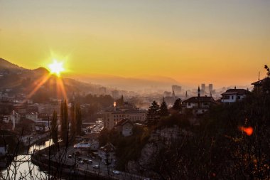 Saraybosna ve Saraybosna Belediye Binası 'nın üzerinde güzel bir gün batımı. Şehrin güzel manzarası ve Saraybosna şehrinin diğer manzaralarının siluetleri..