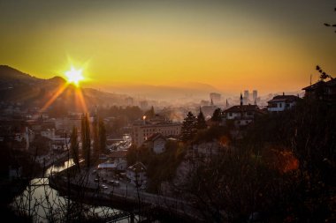 Saraybosna ve Saraybosna Belediye Binası 'nın üzerinde güzel bir gün batımı. Şehrin güzel manzarası ve Saraybosna şehrinin diğer manzaralarının siluetleri..