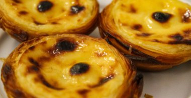 Pankart. Tipik Portekiz kremalı turtaları, Pastel de Nata veya Pastel de Belem. Geleneksel kafede geleneksel Portekiz kremalı pastalarının yakın çekimi: Restoran. Pastel de nata. Pastis de Belm.