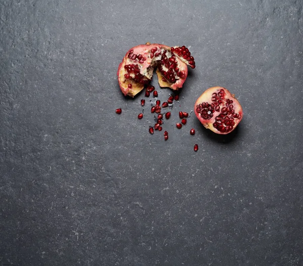 Colourful pomegranate isolated on dark grey stone background. Top view. Healthy and fresh fruits for boosting vitamin C and immunity system, top view.